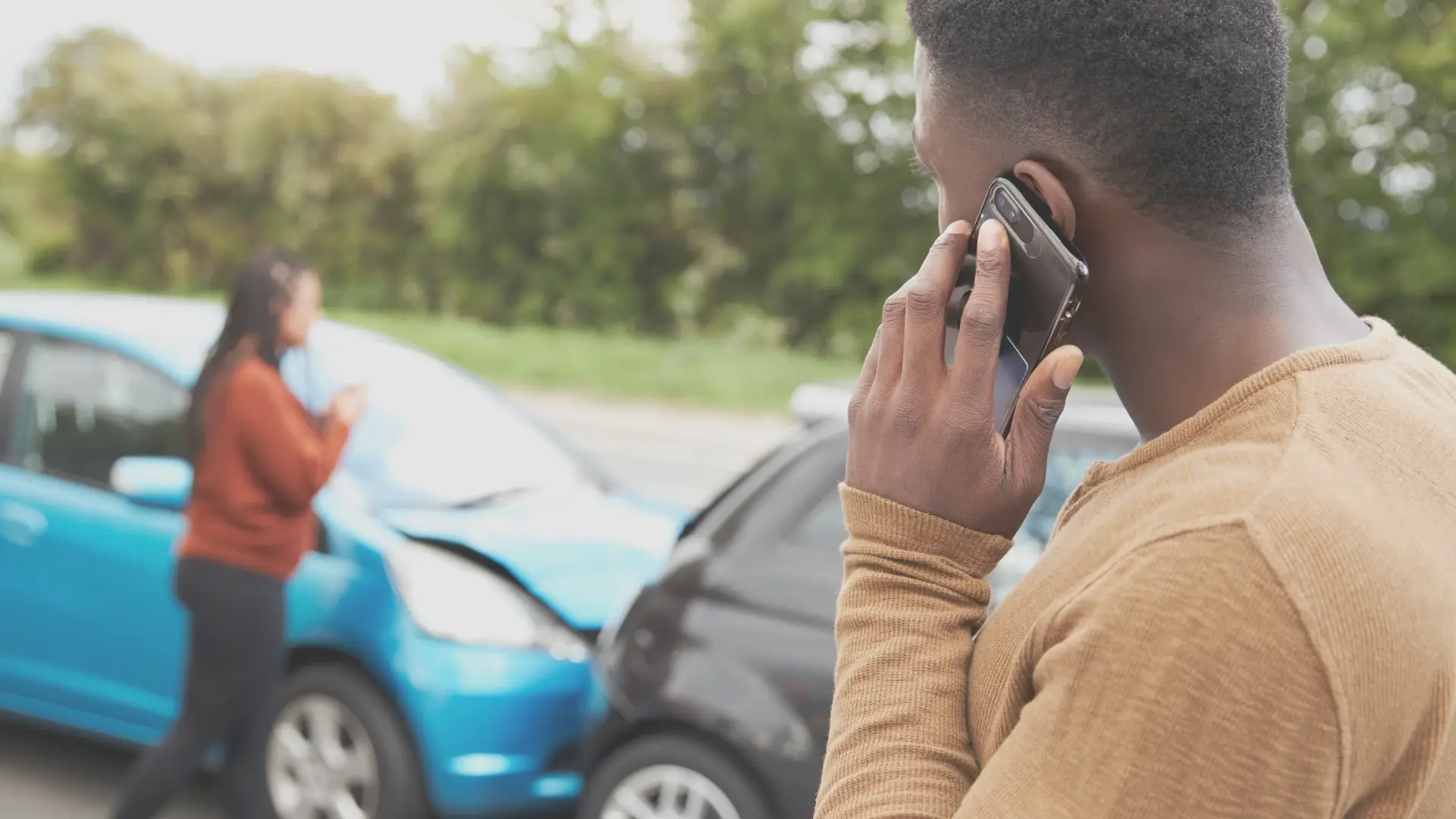 a man speaking to his insurance on the phone after a car accident with another driver